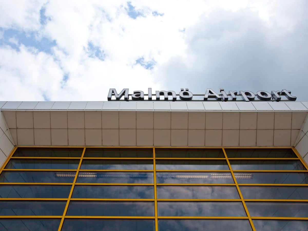 Entrén till terminalen på Malmö Airport i Sturup med skylten Malmö Airport och gulinramade glaspartier