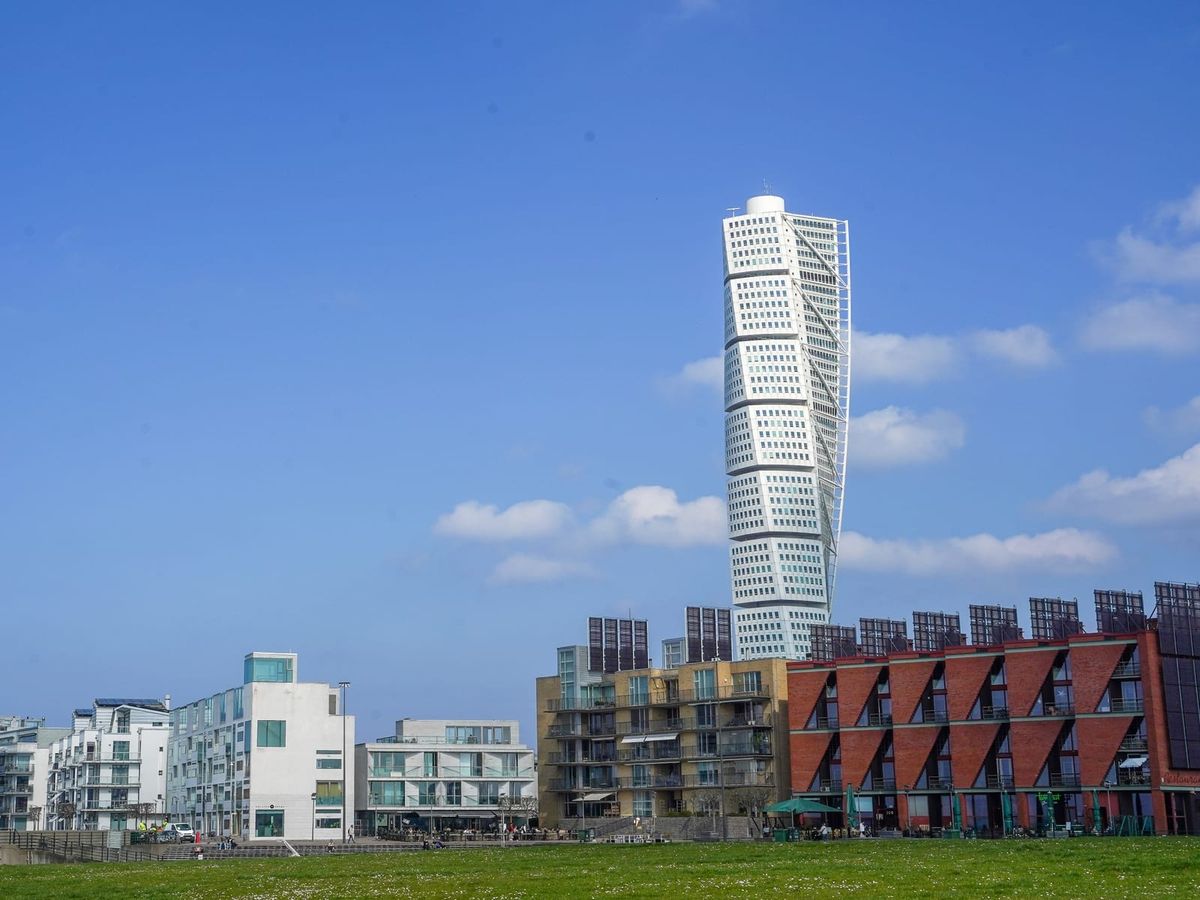 Turning Torso över bostadshusen i Västra hamnen i Malmö, med en gräsmatta i förgrunden